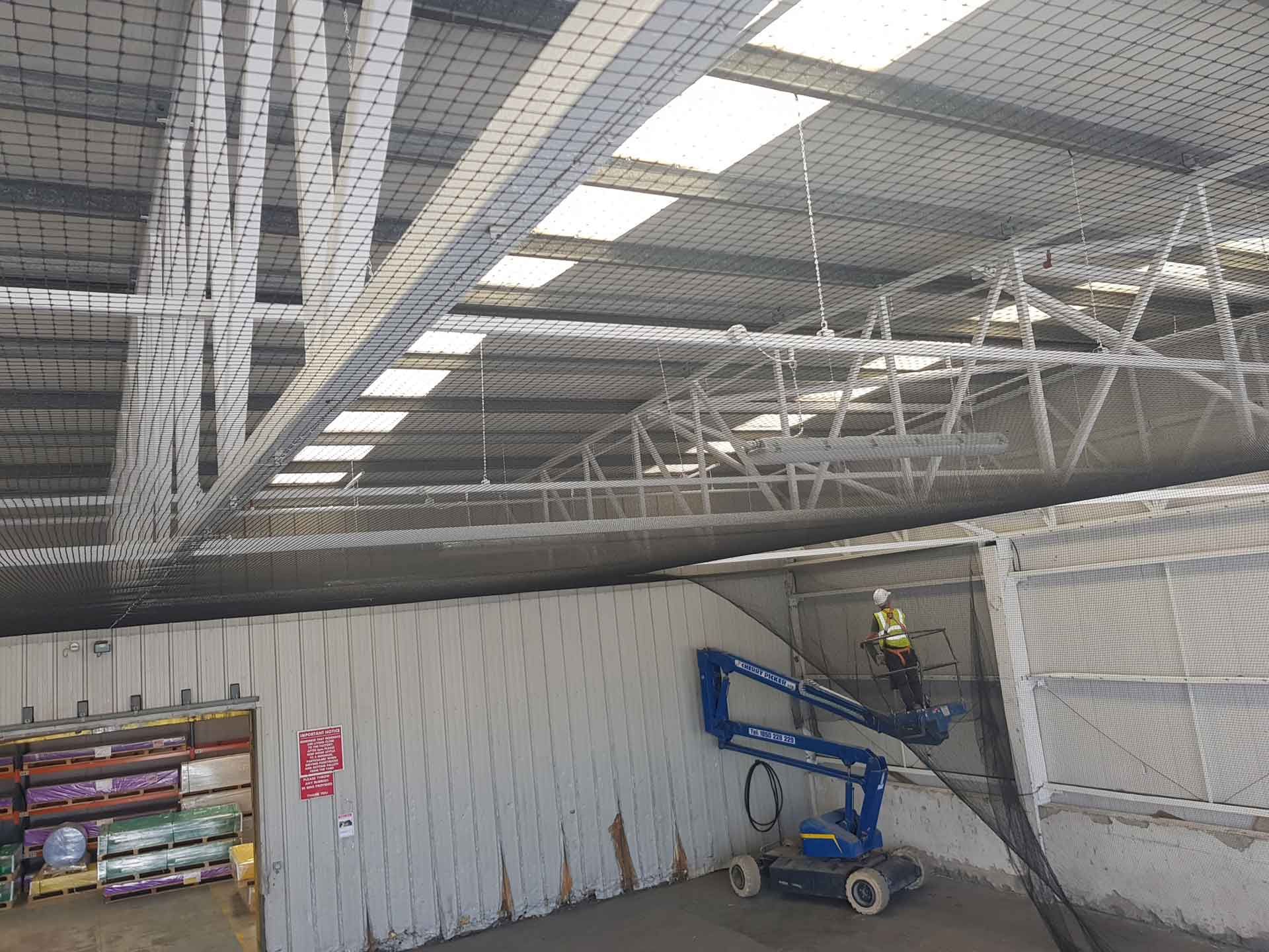 Bird netting being installed in a warehouse